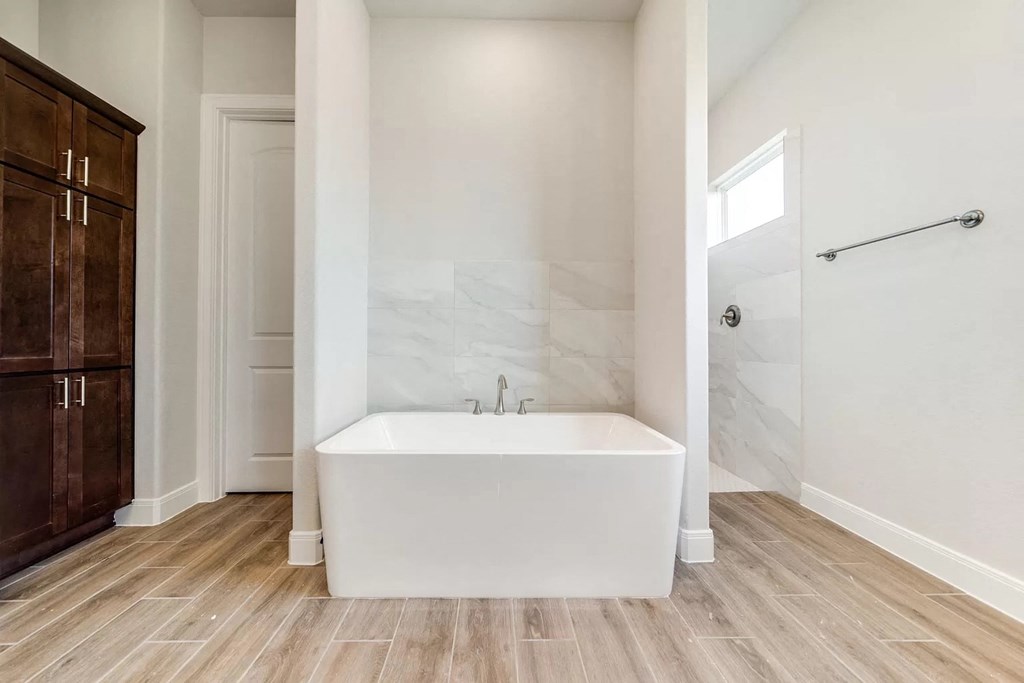 a bathroom with a tub and a shower and a wooden floor