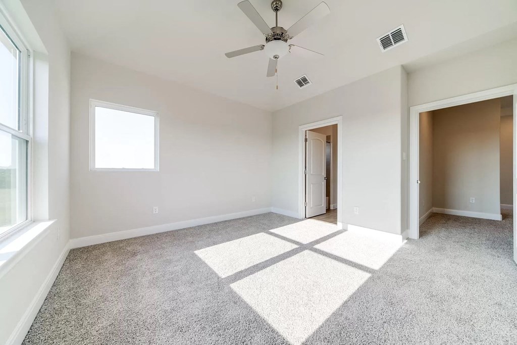 an empty living room with a ceiling fan