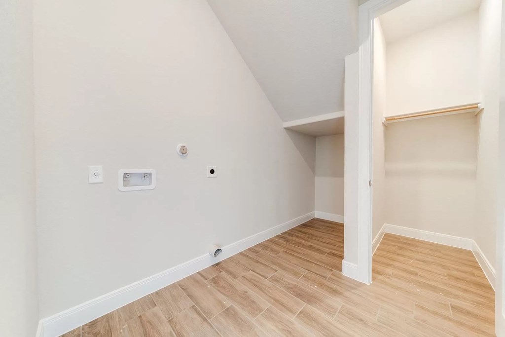a room with wood flooring and white walls and a closet