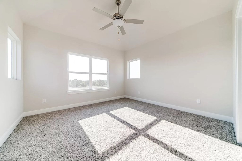 an empty room with a ceiling fan and a window