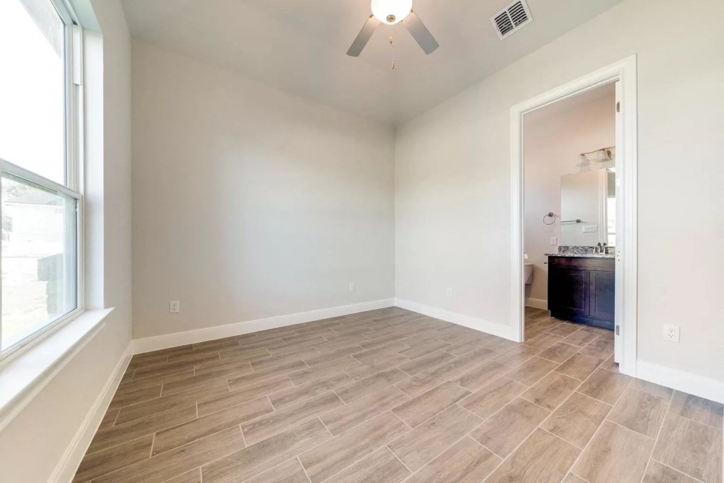 an empty living room with a large window and a bathroom