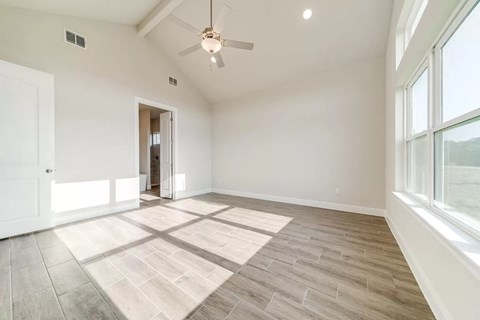 an empty living room with a ceiling fan and a large window