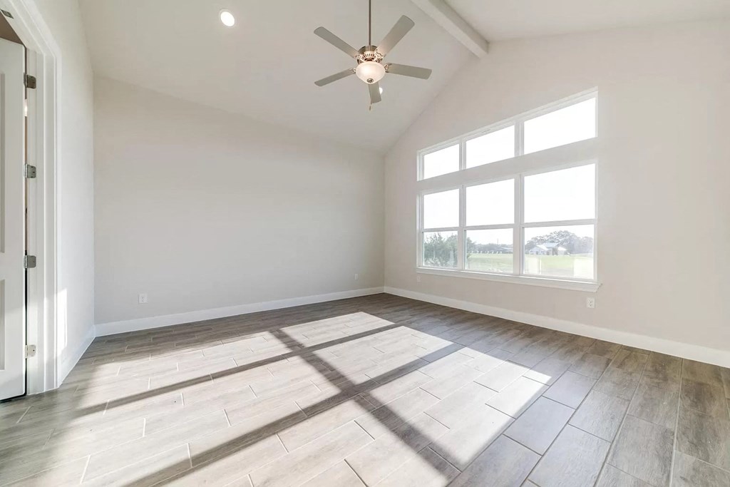an empty living room with a ceiling fan and a window