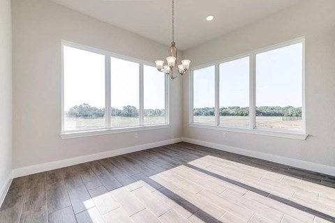 an empty living room with large windows and wood floors