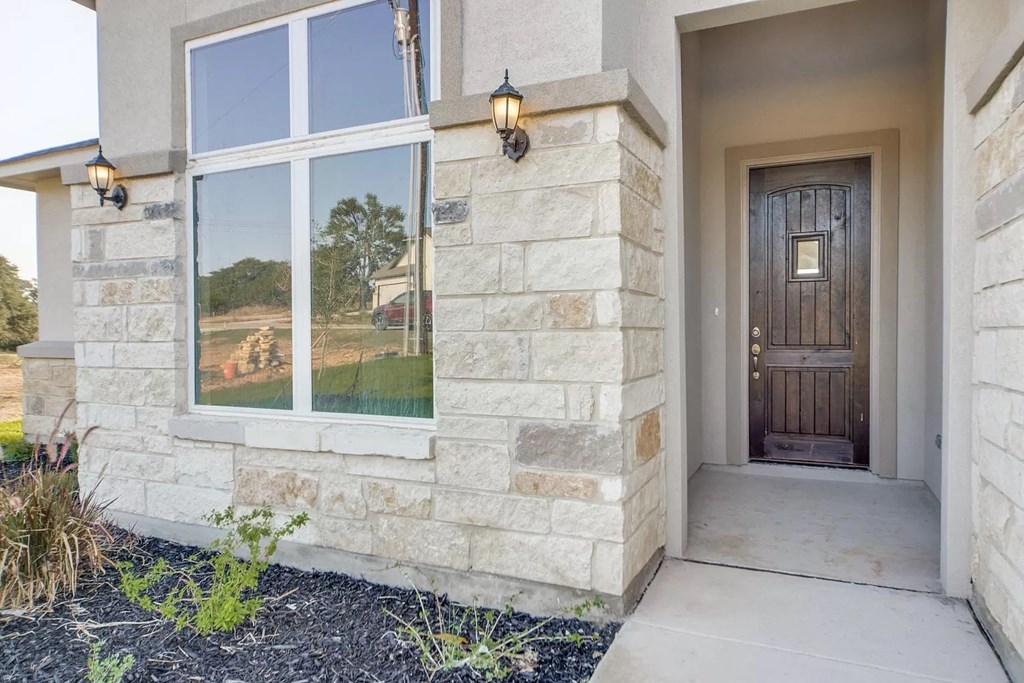 the front porch of a home with a wooden door and a large window