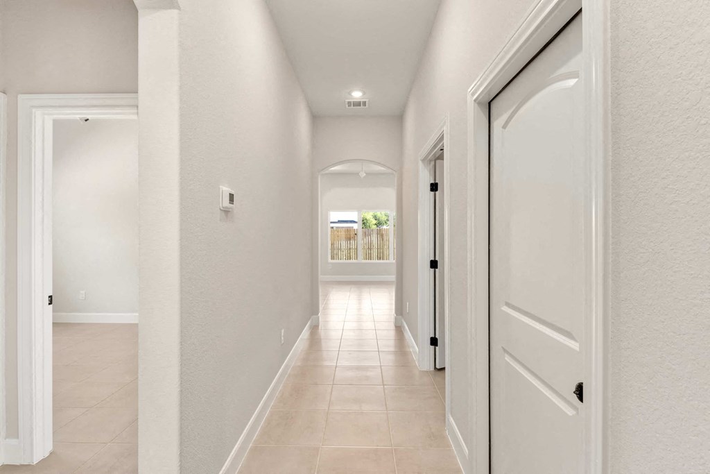 the hallway of a home with white doors and a tiled floor