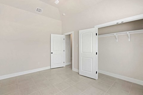 a bedroom with two closets and two doors and a tiled floor
