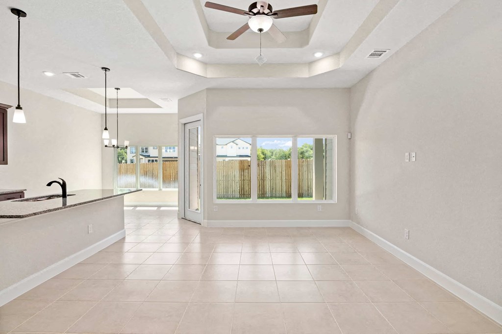 an empty living room with a large window and a ceiling fan