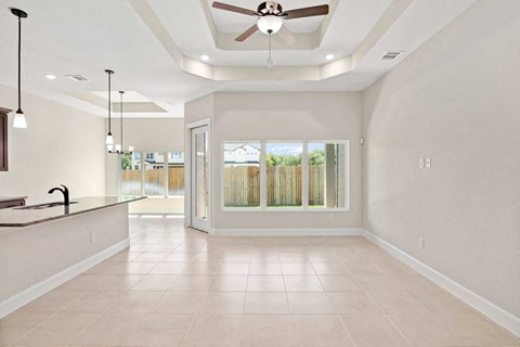 an empty living room with a large window and a ceiling fan