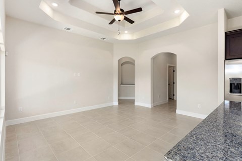 the living room and kitchen of a new home with a ceiling fan
