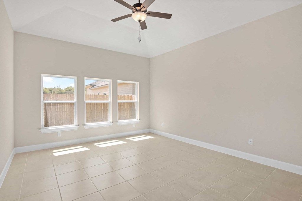 an empty living room with a ceiling fan and windows