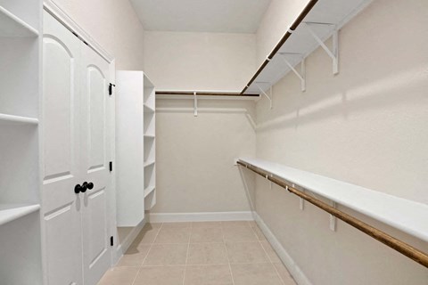 a walk in closet with white closets and a counter