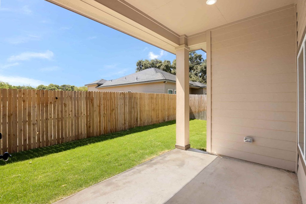 the backyard of a house with a wooden fence and a concrete patio