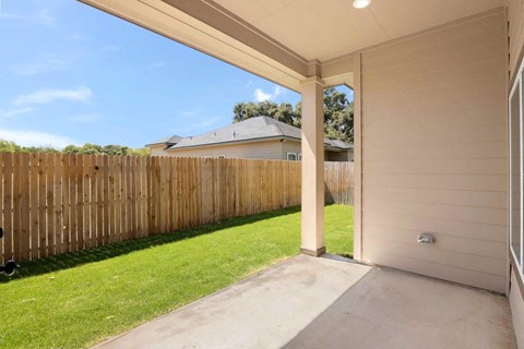 the backyard of a house with a wooden fence and a concrete patio