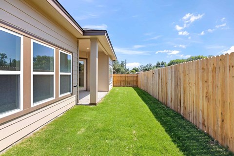 a yard with a wooden fence and a lawn next to a house
