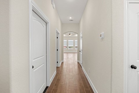 a hallway with white walls and doors and a tiled floor