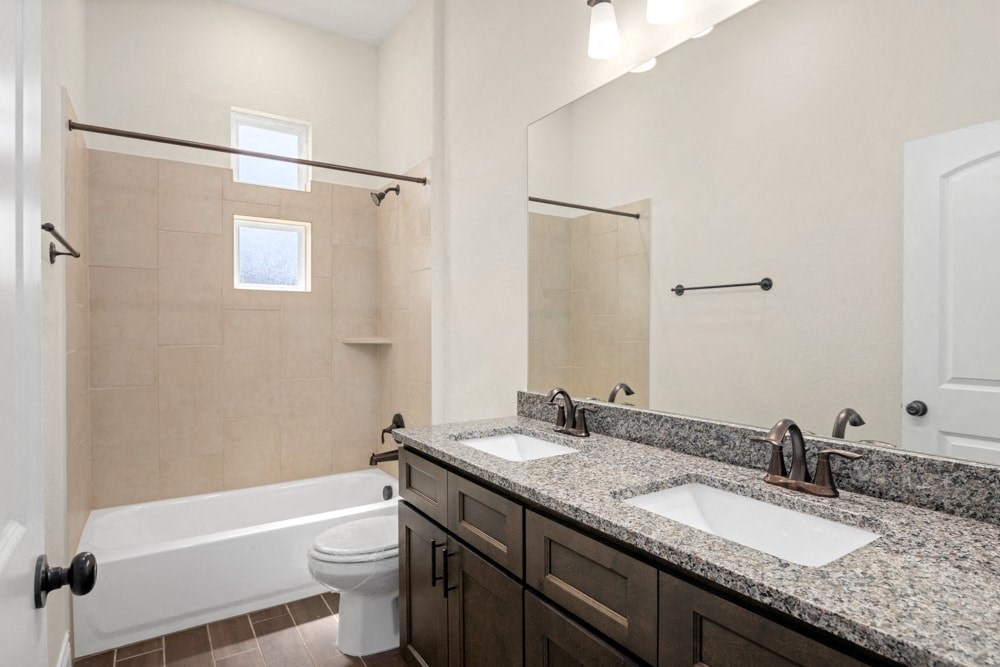 a bathroom with two sinks and a shower and a toilet