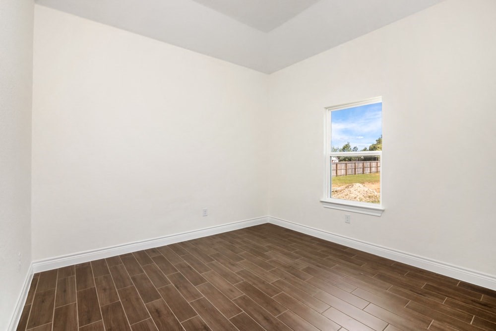 an empty living room with wood flooring and a window
