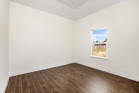an empty living room with wood flooring and a window