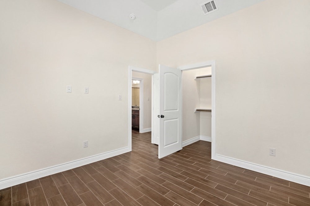 the living room and entryway of an empty home with white walls and wood floor