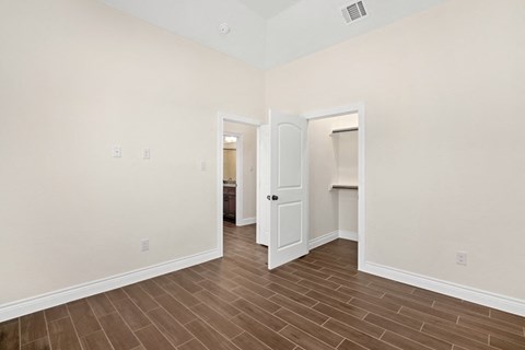 the living room and entryway of an empty home with white walls and wood floor