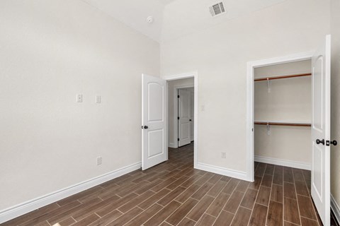 the living room and closet of an empty apartment with wood flooring