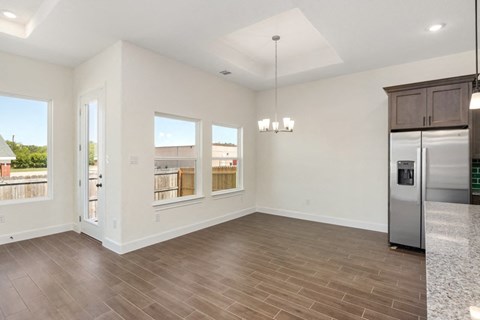 the living room and kitchen of a new home with a stainless steel refrigerator