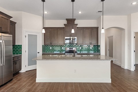 an open kitchen with an island with a granite counter top