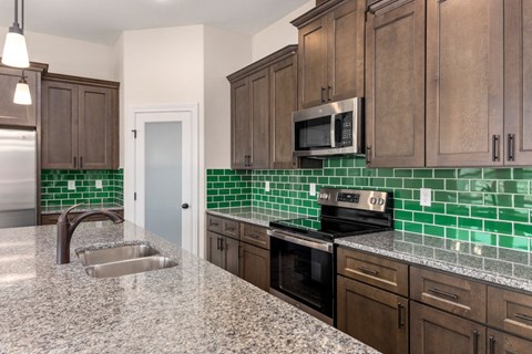 an updated kitchen with green tile and wooden cabinets