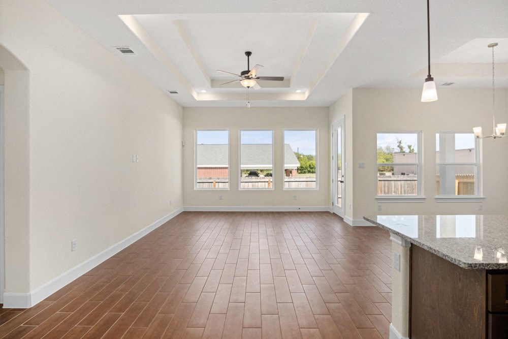 an empty living room with a ceiling fan and windows