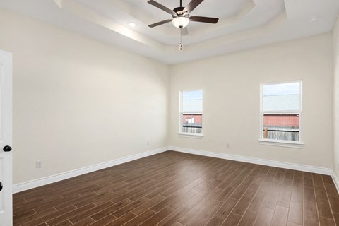 an empty living room with wood flooring and a ceiling fan