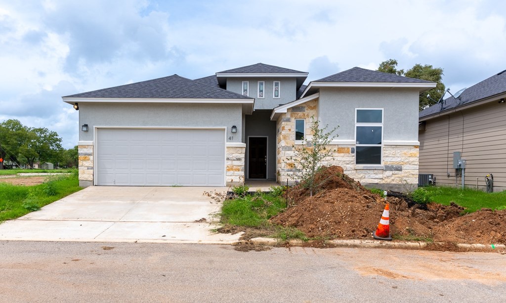 a house with a driveway and a pile of dirt in front of it
