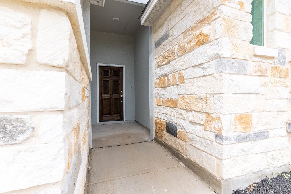 an empty hallway with a stone wall and a door to a house