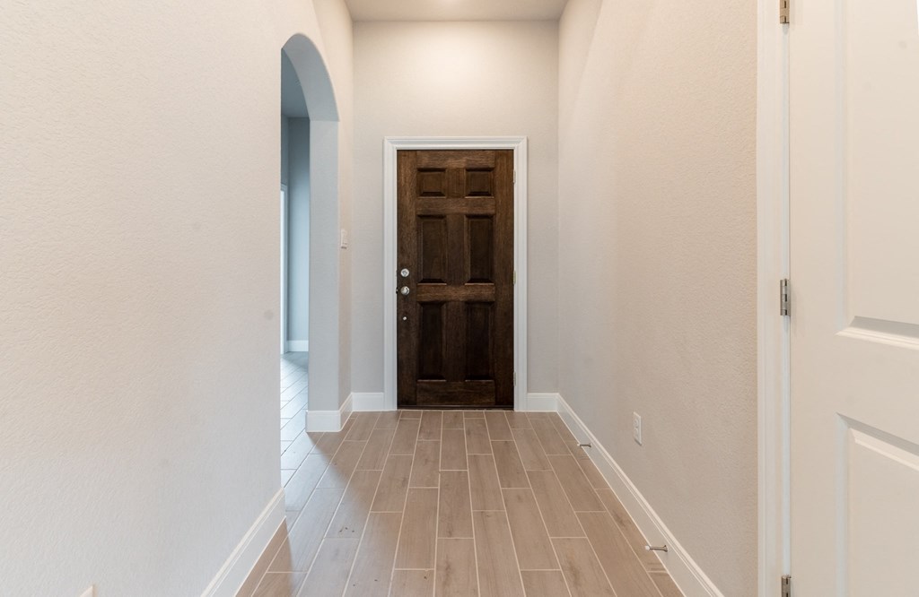 an empty hallway with a wooden door in a home