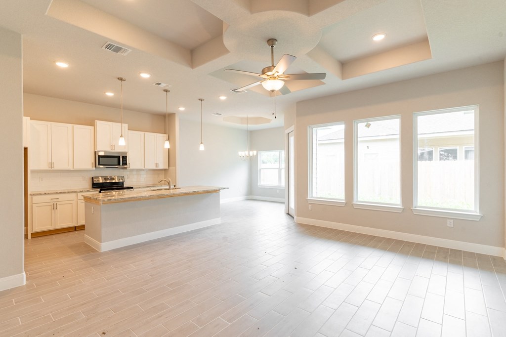 an empty kitchen and living room with a ceiling fan
