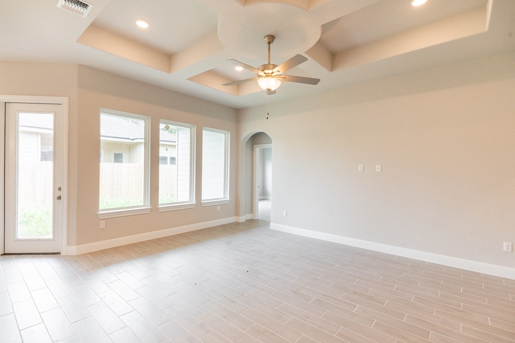 an empty living room with a ceiling fan and windows