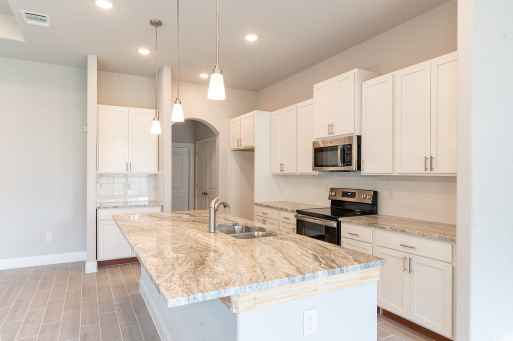 a kitchen with white cabinets and a marble counter top