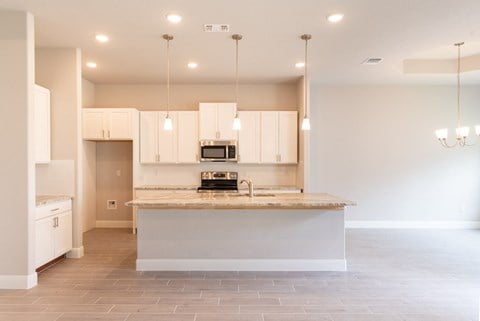 a kitchen with white cabinets and a marble counter top