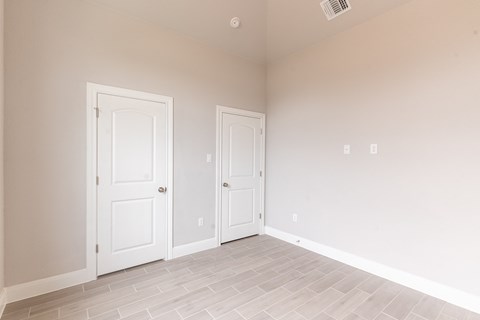 an empty bedroom with two doors and a tiled floor
