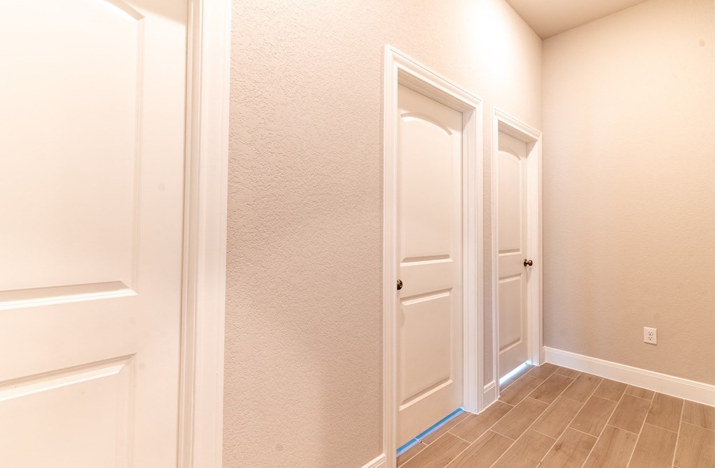 an empty hallway with two doors and a door to a closet