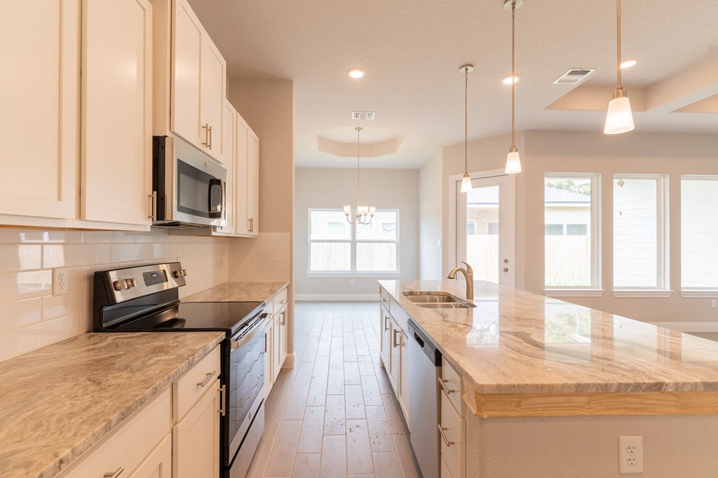a large kitchen with marble counter tops and white cabinets