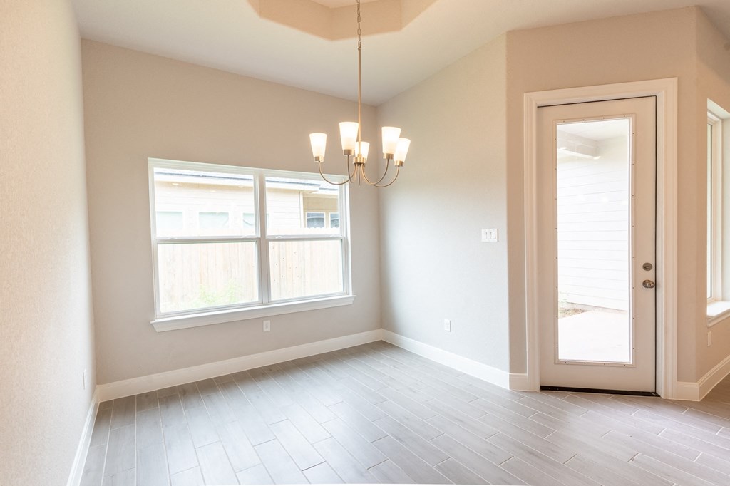 an empty living room with a chandelier and window