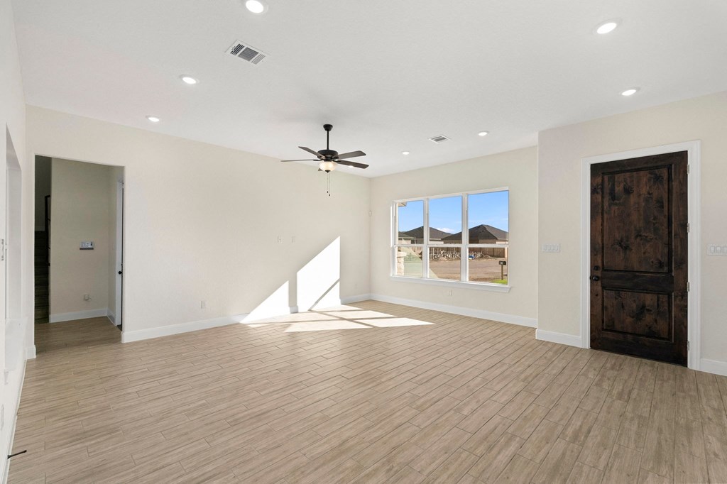 an empty living room with a ceiling fan and a window