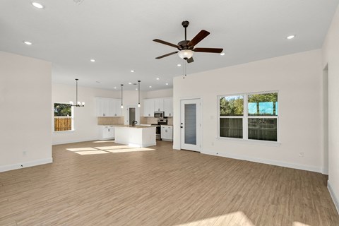 a living room with a ceiling fan and a kitchen