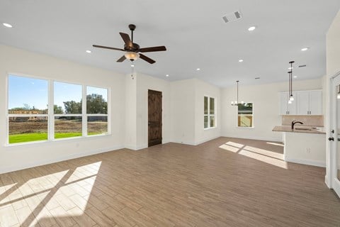an empty living room with a ceiling fan and a window