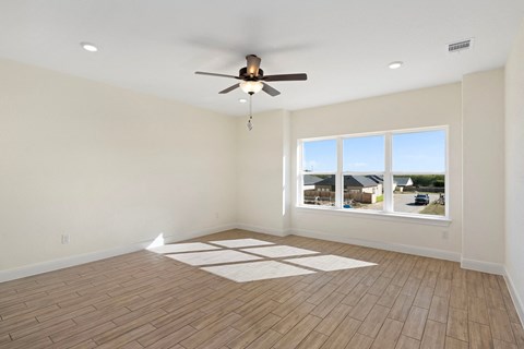 an empty living room with a ceiling fan and a window