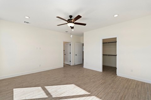 a empty living room with a ceiling fan and a closet