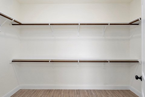 an empty closet with white walls and a wood floor