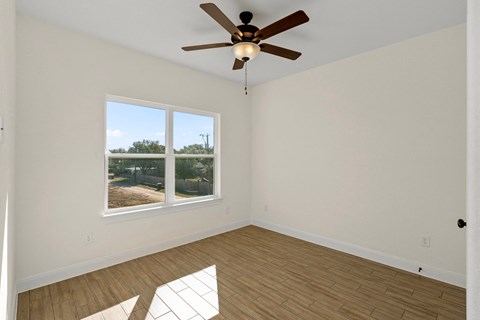 an empty living room with a ceiling fan and a window
