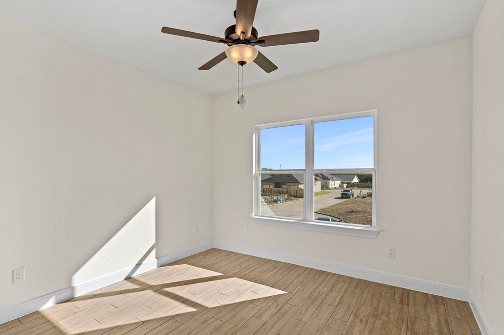 an empty living room with a ceiling fan and a window